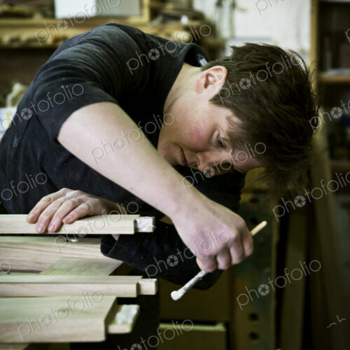 A woman working in a furniture maker's workshop using a small brush to apply glue to… A woman working in a furniture maker's workshop using a small brush to apply glue to…