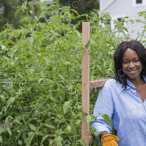 A woman working in the garden. Leaning on a fence smiling. A woman working in the garden. Leaning on a fence smiling.