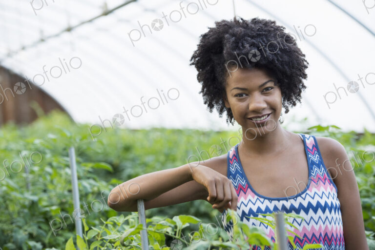 A woman working in the glasshouse, tending plants on a greenhouse bench.
