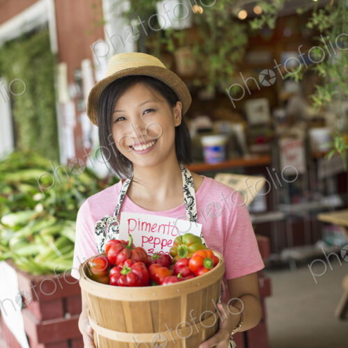 A woman working on an organic farm stand, displaying fresh vegetables for sale. A woman working on an organic farm stand, displaying fresh vegetables for sale.