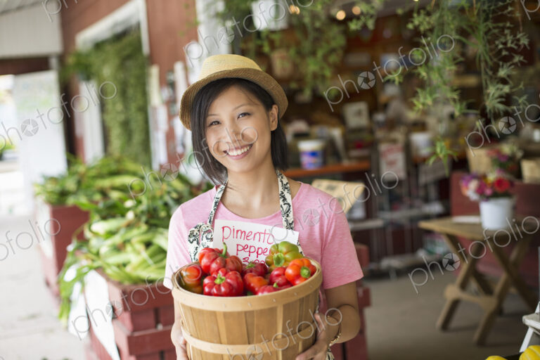 A woman working on an organic farm stand, displaying fresh vegetables for sale.