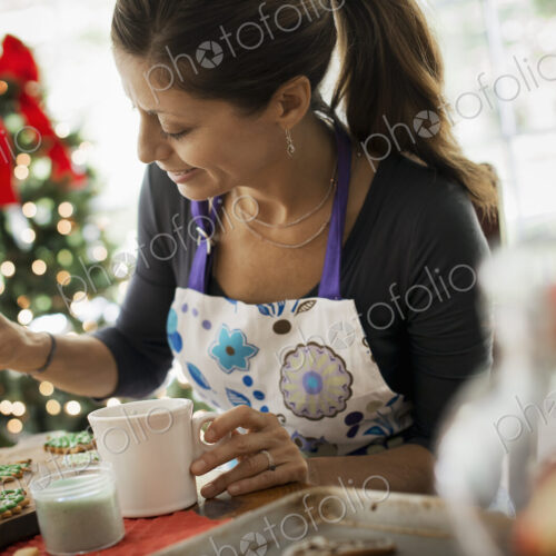 A woman working on organic homemade Christmas cookies, decorating and sprinkling… A woman working on organic homemade Christmas cookies, decorating and sprinkling…