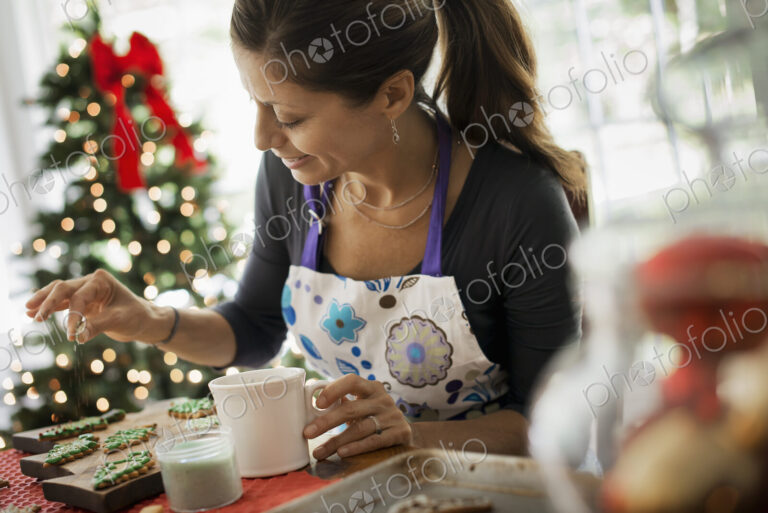 A woman working on organic homemade Christmas cookies, decorating and sprinkling…