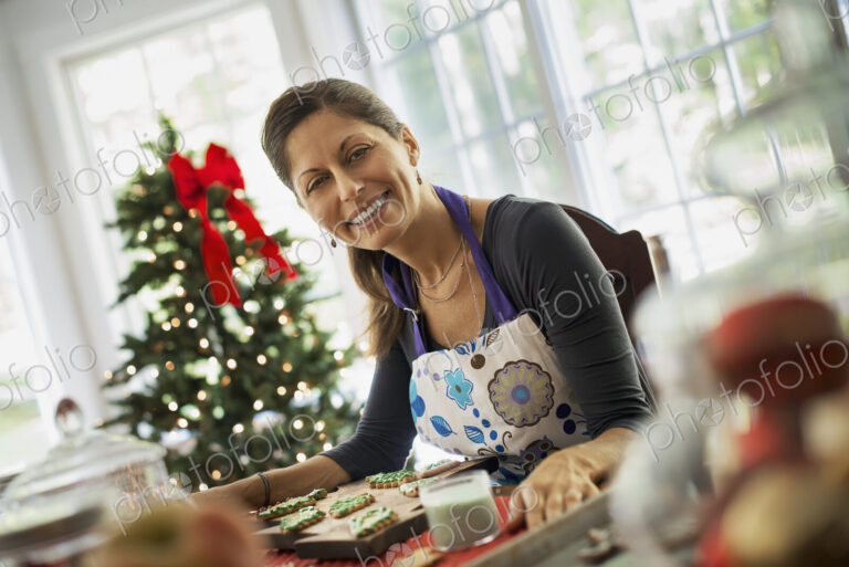 A woman working on organic homemade Christmas cookies, decorating and sprinkling…