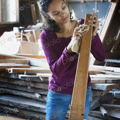 A woman working with reclaimed timber in a woodwork workshop.