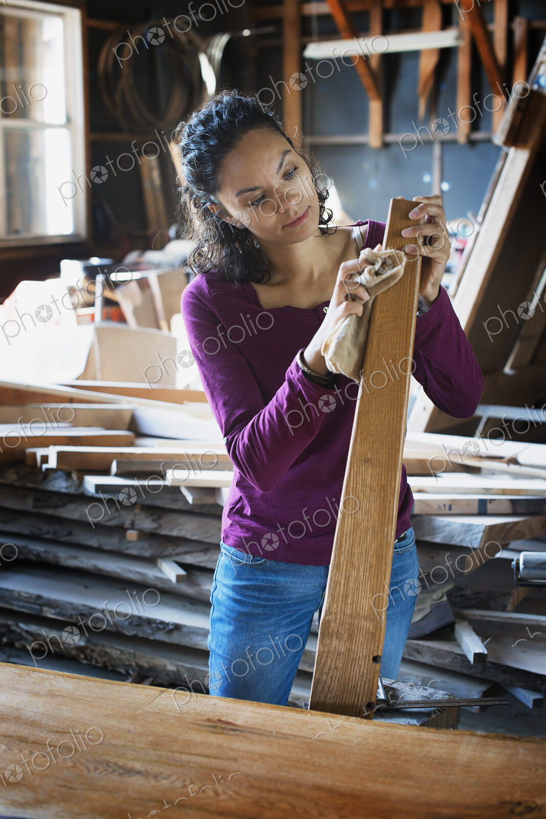 A woman working with reclaimed timber in a woodwork workshop.