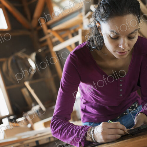 A woman working with reclaimed timber in a woodwork workshop.