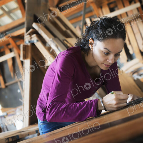 A woman working with reclaimed timber in a woodwork workshop.