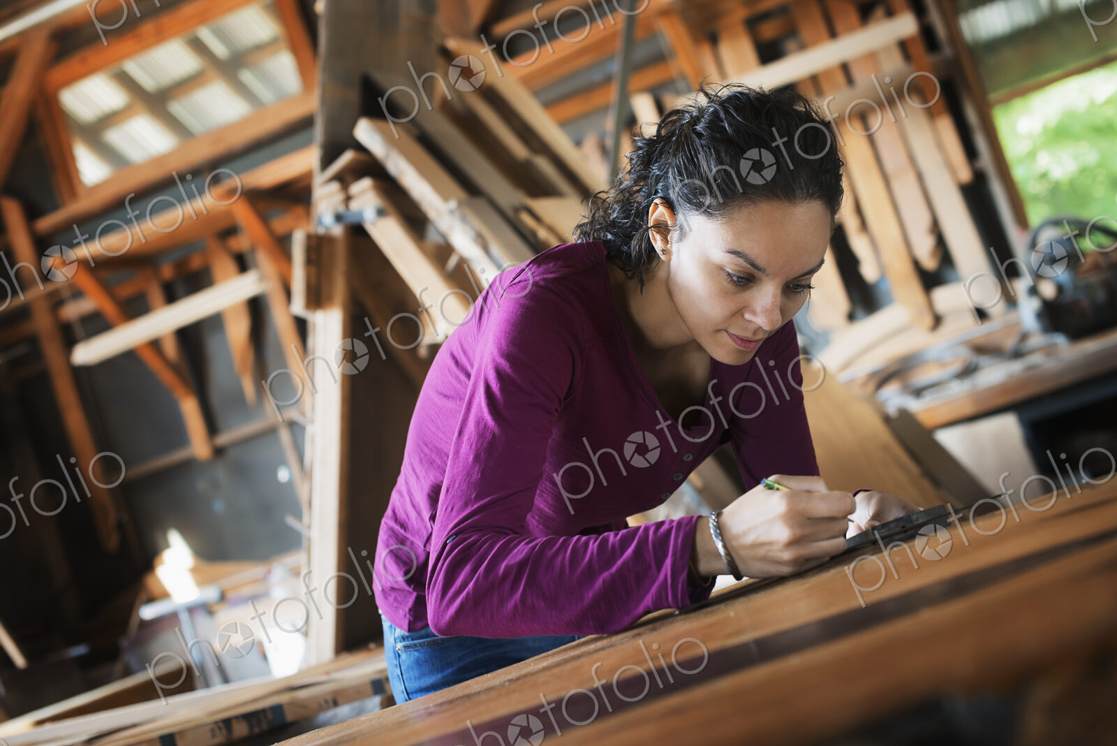 A woman working with reclaimed timber in a woodwork workshop.