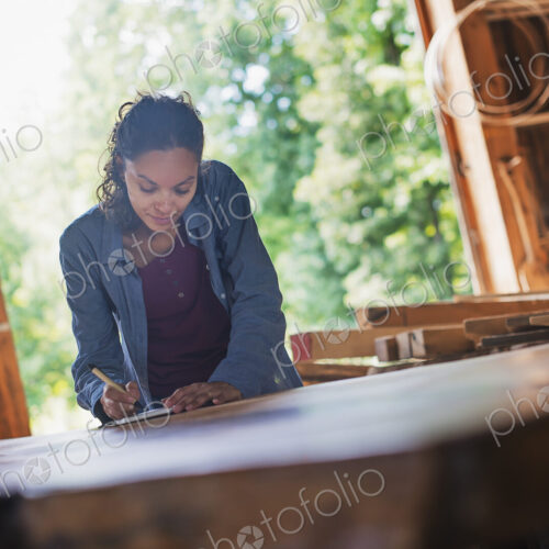 A woman working with reclaimed timber in a woodwork workshop.