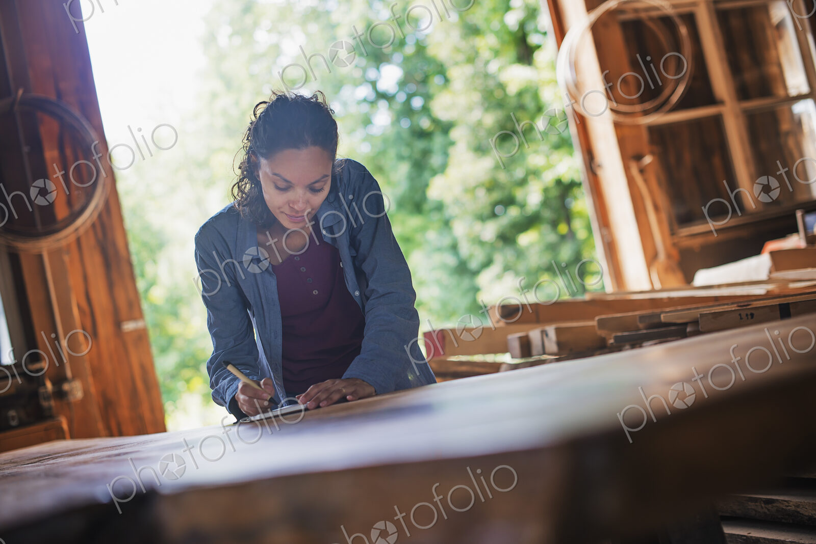A woman working with reclaimed timber in a woodwork workshop.