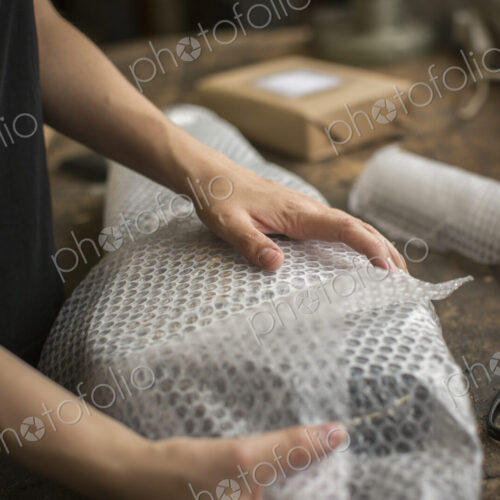A woman wrapping an item in bubble wrap, a parcel being prepared for despatch. A woman wrapping an item in bubble wrap, a parcel being prepared for despatch.