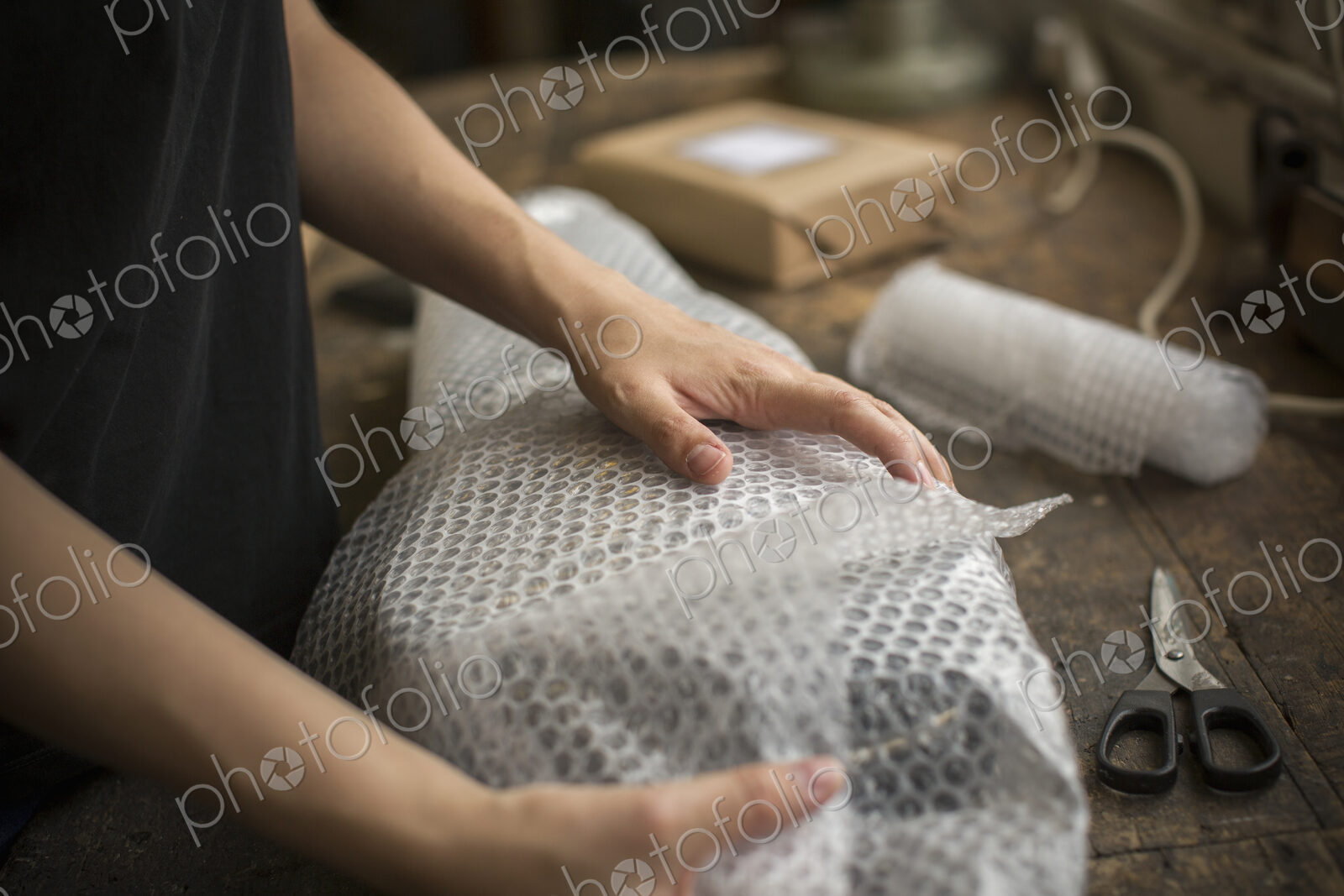 A woman wrapping an item in bubble wrap, a parcel being prepared for despatch.