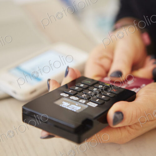 A woman's hands holding a credit card reader, processing payment or paying for goods. A woman's hands holding a credit card reader, processing payment or paying for goods.