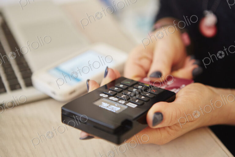 A woman's hands holding a credit card reader, processing payment or paying for goods.
