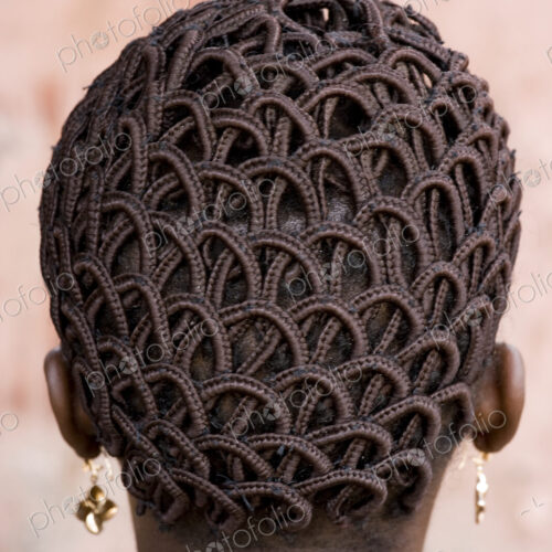 A woman's head with braided patterned hair and earrings. A woman's head with braided patterned hair and earrings.