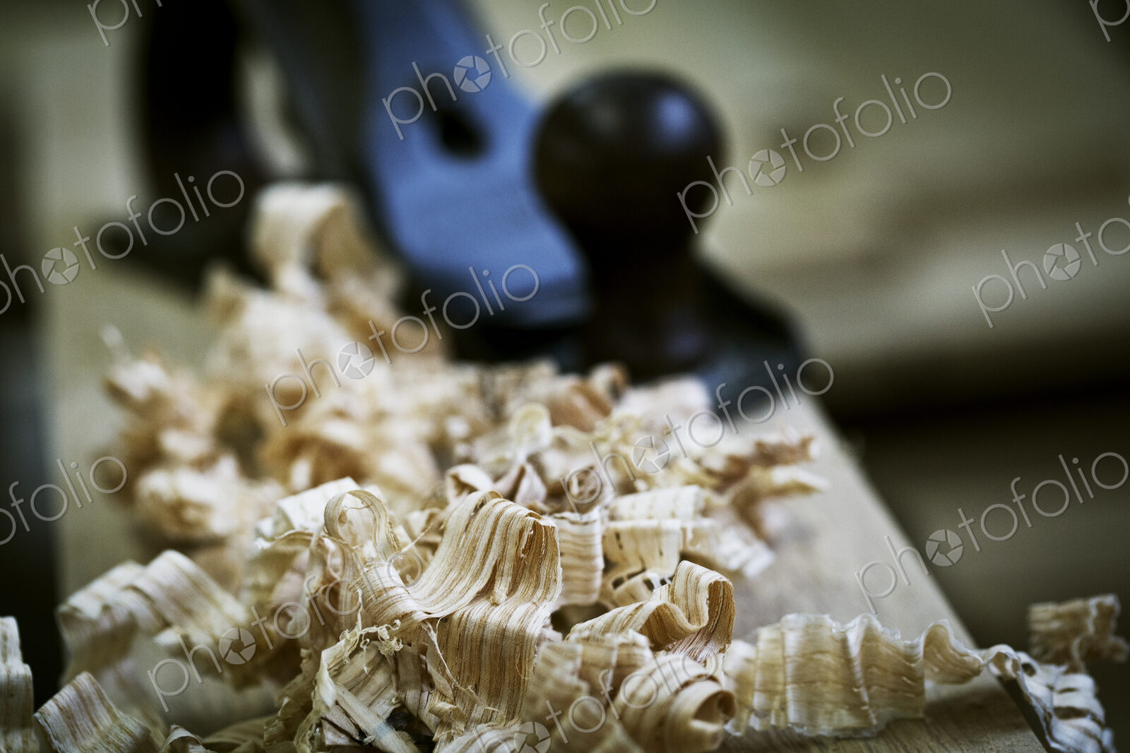 A wood plane on a piece of wood and wood shavings.