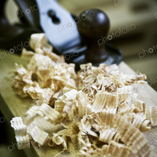 A wood plane on a piece of wood and wood shavings. A wood plane on a piece of wood and wood shavings.