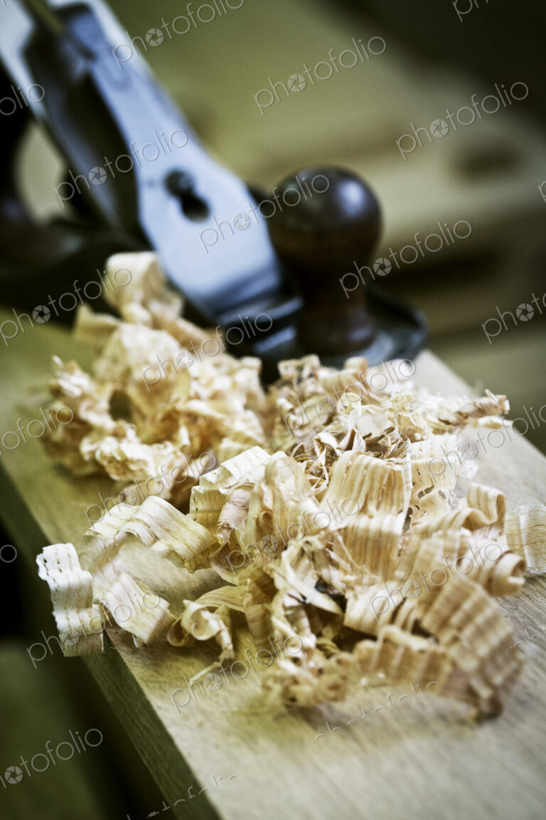 A wood plane on a piece of wood and wood shavings.