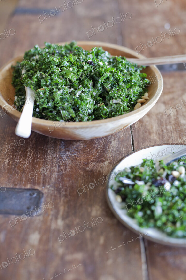 A wooden kitchen tabletop. Two plates of fresh green salad vegatables. Organic fresh food.