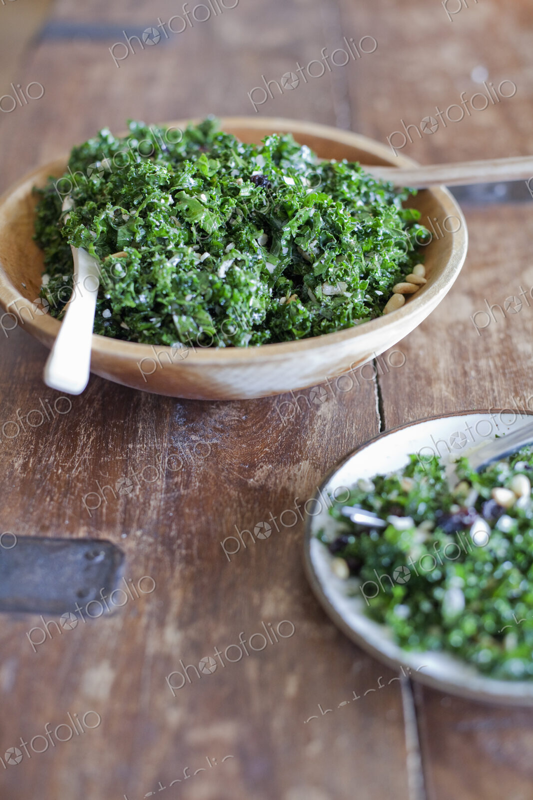 A wooden kitchen tabletop. Two plates of fresh green salad vegatables. Organic fresh food.