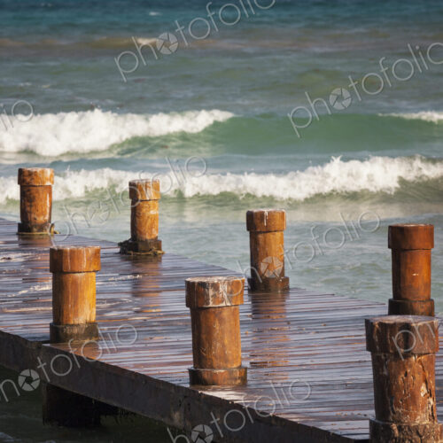 A wooden pier with posts or bollards on the coastline A wooden pier with posts or bollards on the coastline