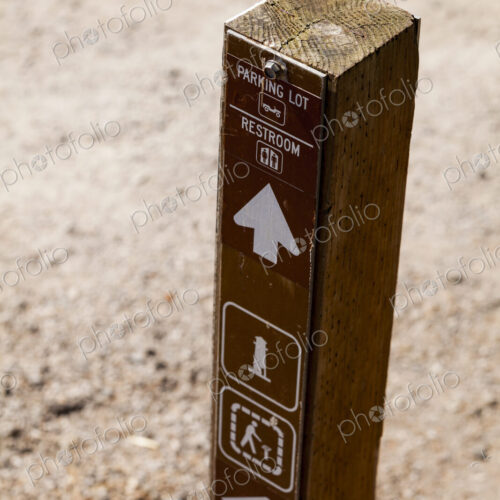 A wooden post with information and directional arrows, to the Parking Lot, Restroom in…