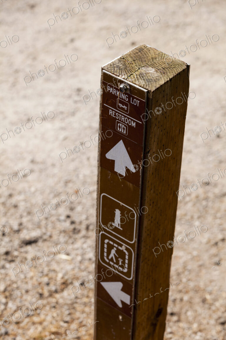 A wooden post with information and directional arrows, to the Parking Lot, Restroom in…