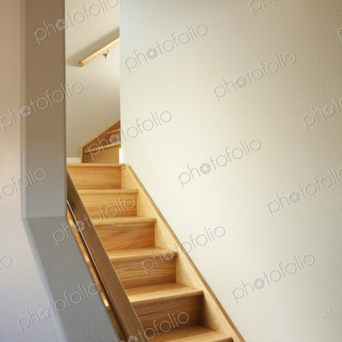 A wooden stair case with two turns in a narrow space in a house.