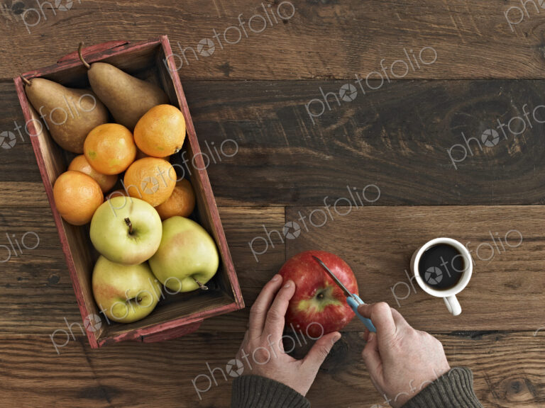A wooden table top with variety of wood colour and grain. A box of fresh fruits, pears…
