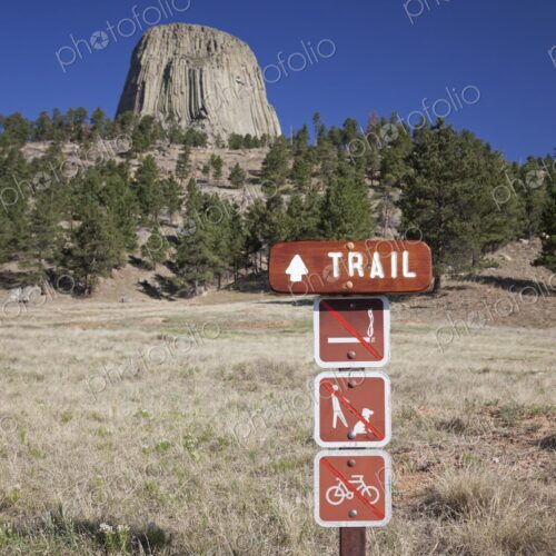 A wooden trail sign with hiking regulations stands in front of Devil's Tower National… A wooden trail sign with hiking regulations stands in front of Devil's Tower National…
