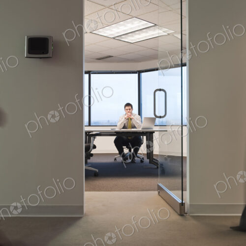 A working conference room with people walking by in the hallway.