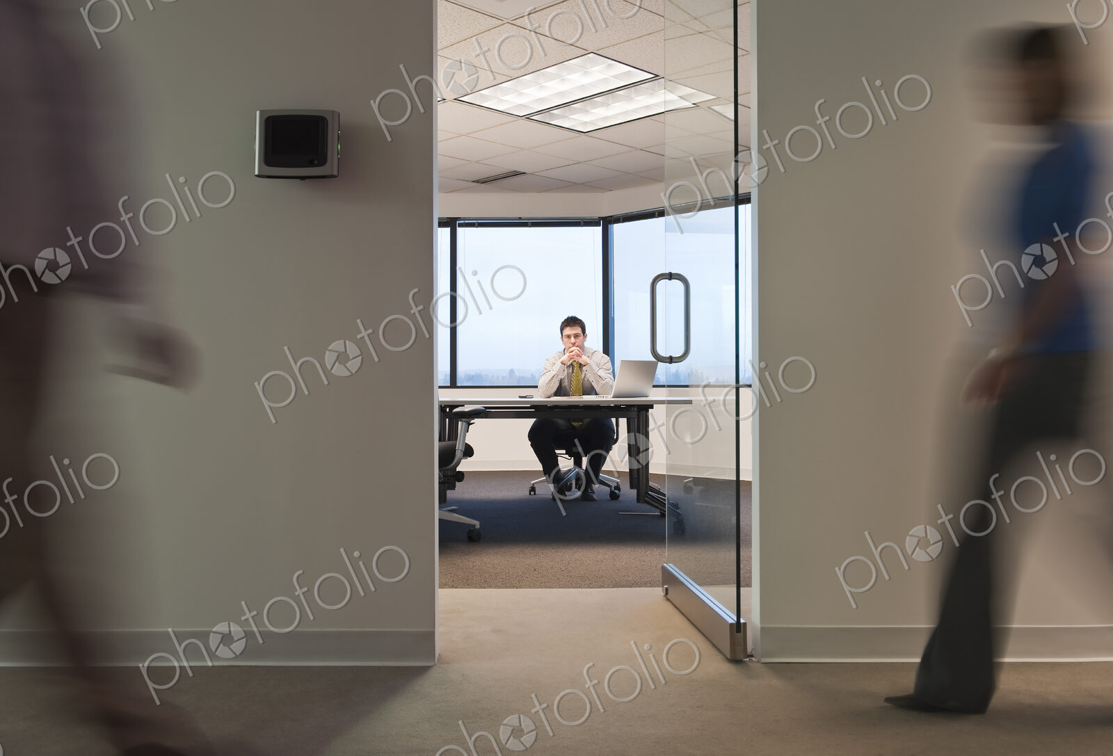A working conference room with people walking by in the hallway.