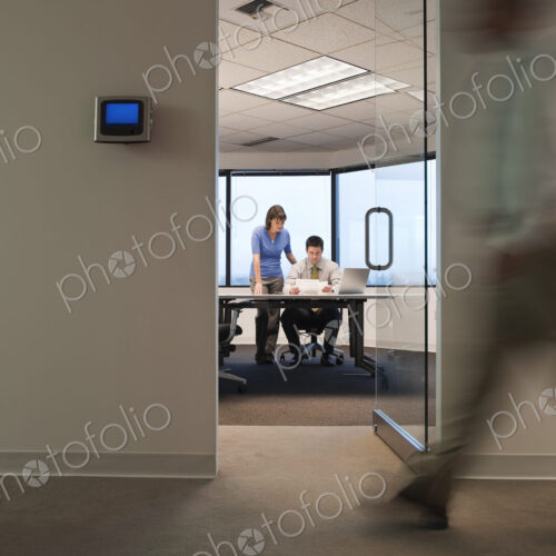 A working conference room with people walking by in the hallway.