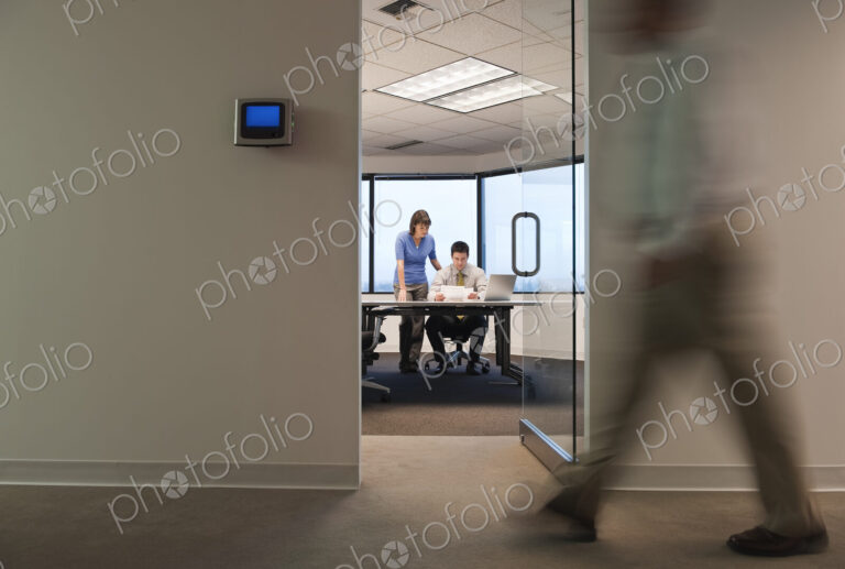 A working conference room with people walking by in the hallway.