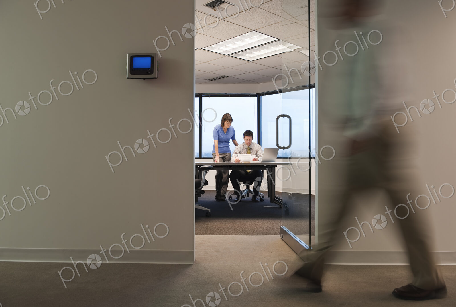 A working conference room with people walking by in the hallway.
