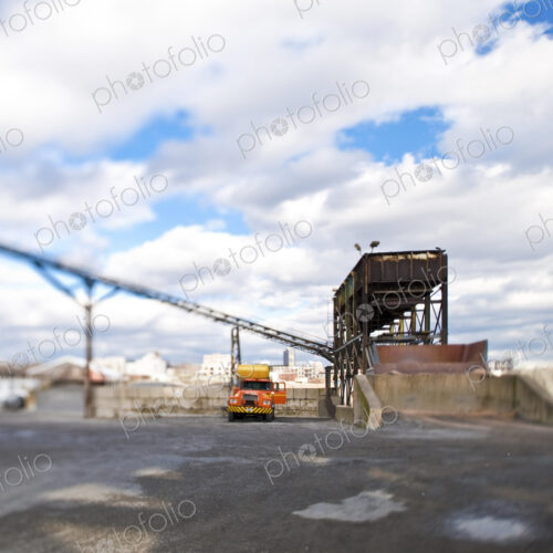 A yellow truck parked at a loading bay, elevated weighbridge and overhead bridge.