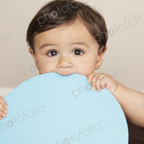A young 8 month old baby boy wearing cloth diapers, holding a large blue disc and… A young 8 month old baby boy wearing cloth diapers, holding a large blue disc and…