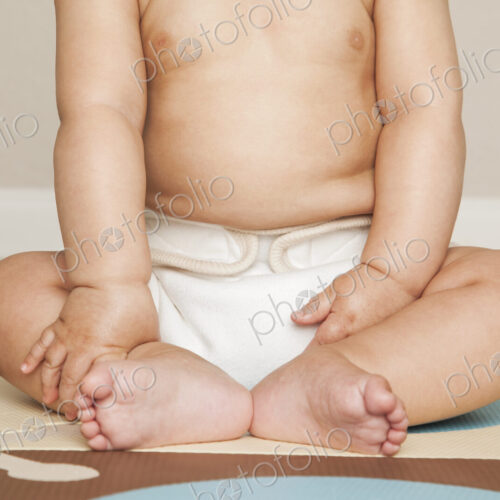 A young 8 month old baby boy wearing cloth diapers, sitting on the floor. A young 8 month old baby boy wearing cloth diapers, sitting on the floor.