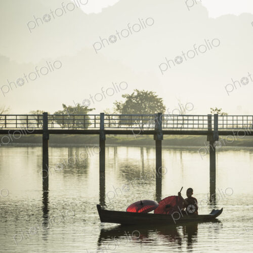 A young Buddist monk paddling a wooden boat along a river. A young Buddist monk paddling a wooden boat along a river.