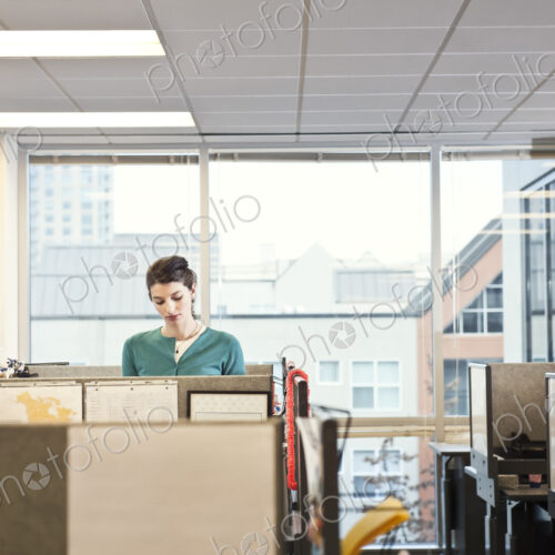 A young Caucasian businesswoman working in her cubicle in a corporate office.