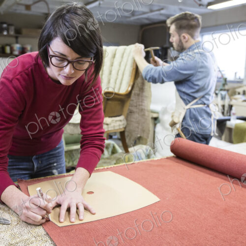 A young Caucasian couple working on a chair as a team of upholsterers.