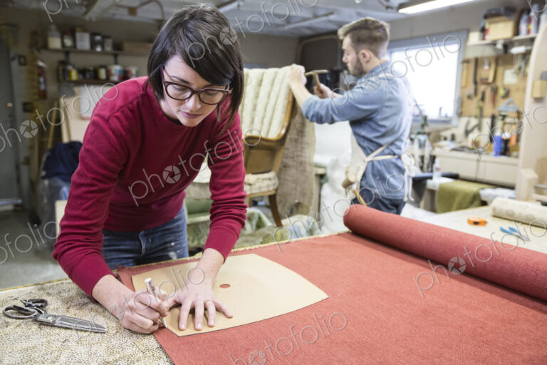 A young Caucasian couple working on a chair as a team of upholsterers.