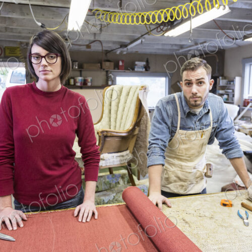 A young Caucasian couple working on a chair as a team of upholsterers.