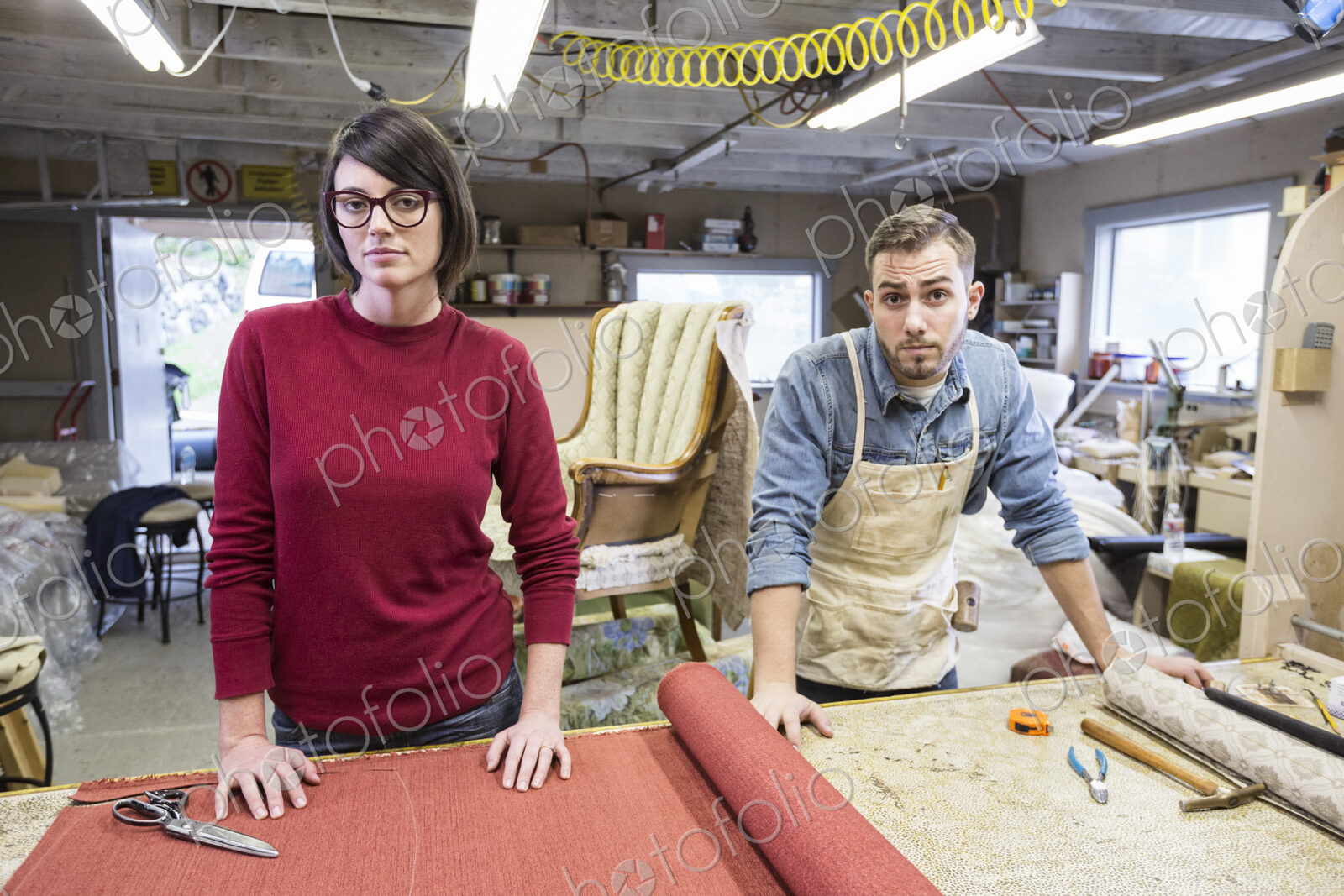 A young Caucasian couple working on a chair as a team of upholsterers.