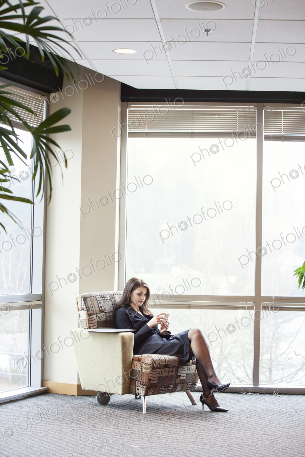 A young Caucasian woman checking her phone in an office lobby.