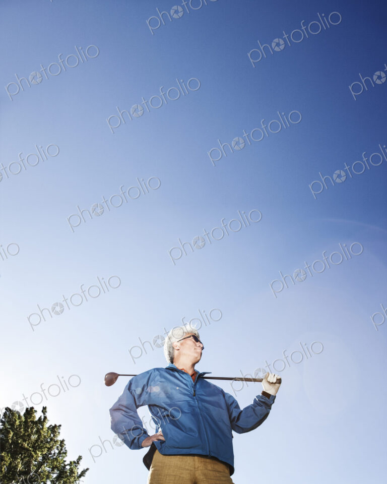 A young asian senior man ready to hit his next golf shot on a golf course.