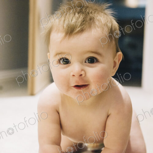 A young baby crawling on a rug.