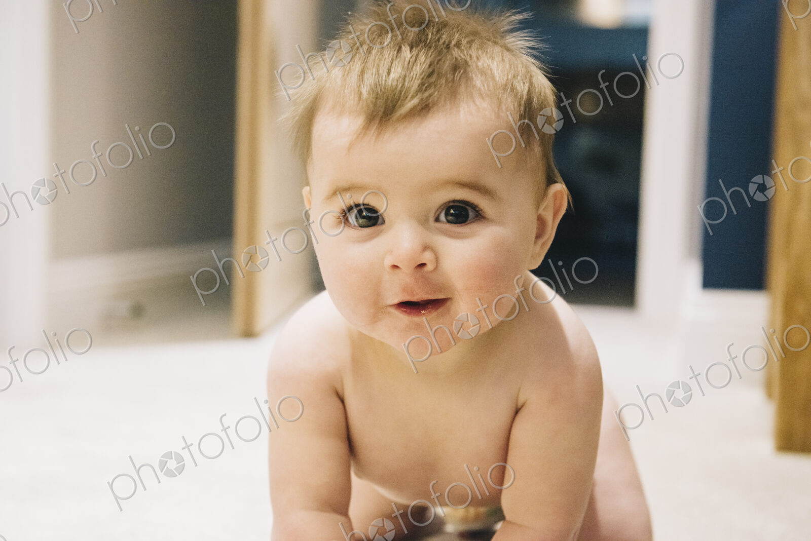 A young baby crawling on a rug.