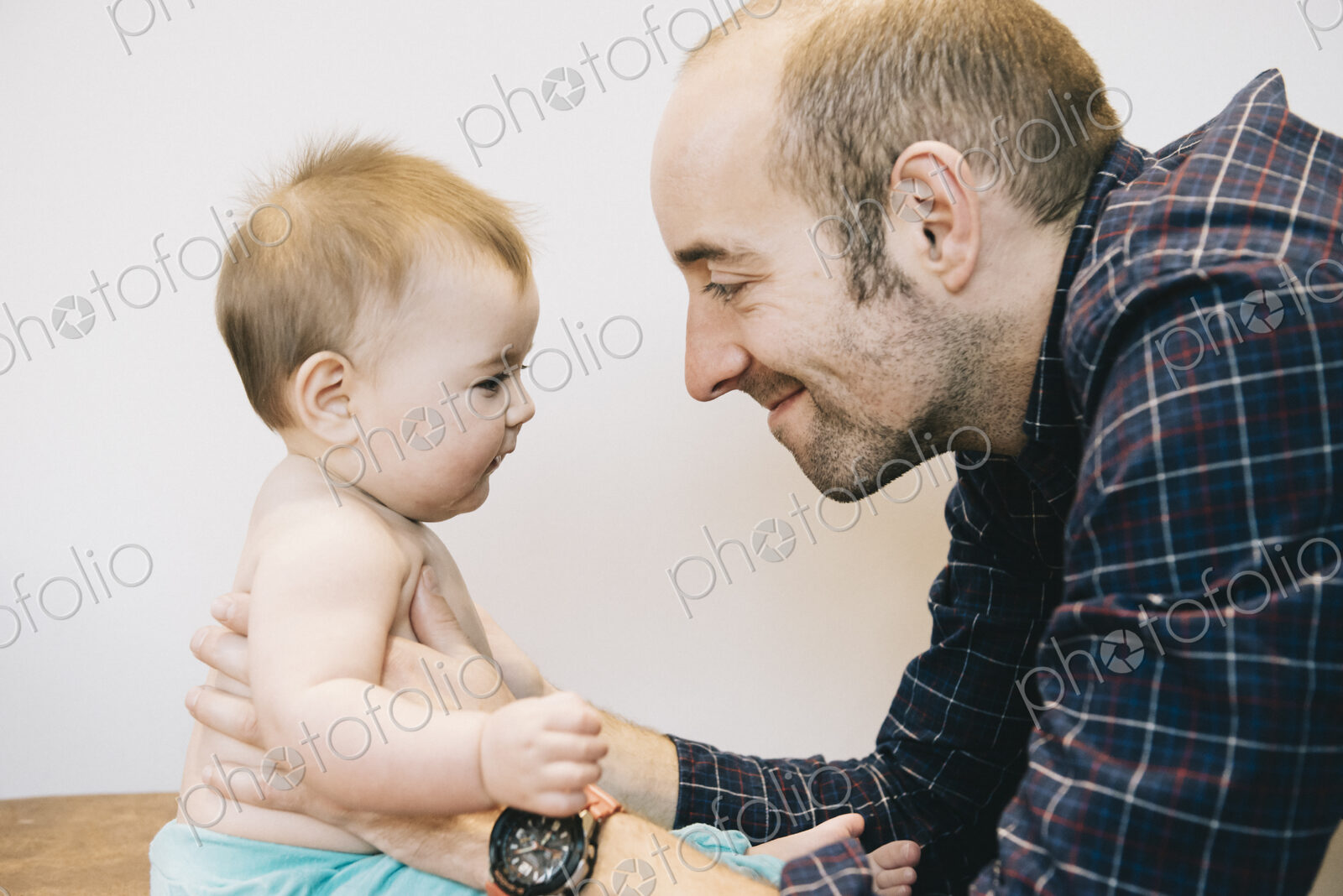A young baby girl and her father face to face playing.